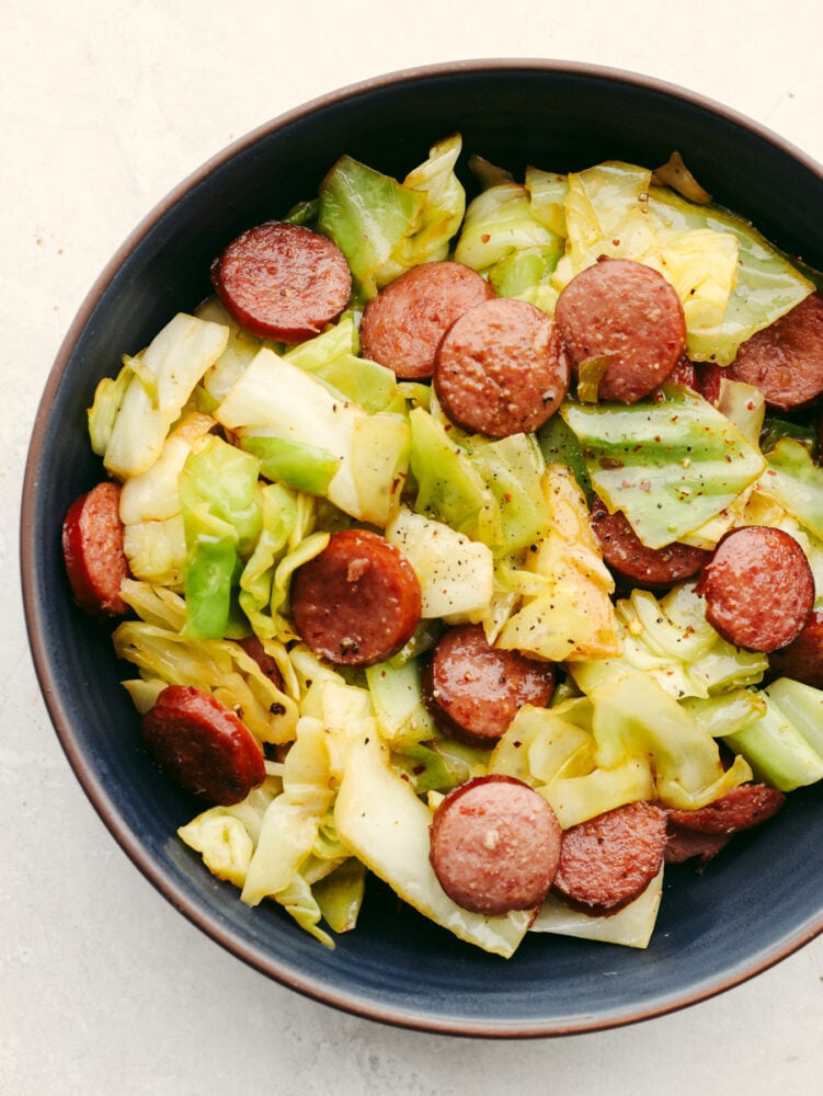 Sausage and cabbage is the easiest skillet recipe to throw together! In minutes, you'll have a tasty meal loaded with amazing meaty flavor and texture! Sausage and cabbage in a blue bowl.