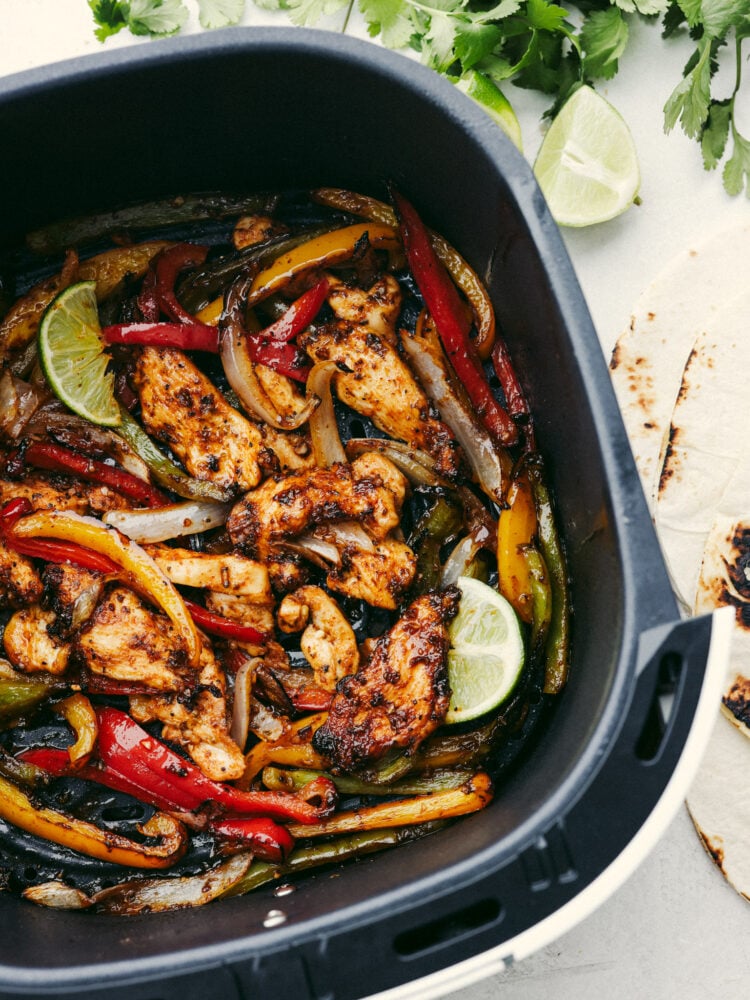 These air fryer fajitas are packed to the brim with flavor but only take a few minutes to make! They are perfect for those on-the-go, busy nights, and everyone will go crazy over them! An air fryer basket filled with cooked chicken fajitas.
