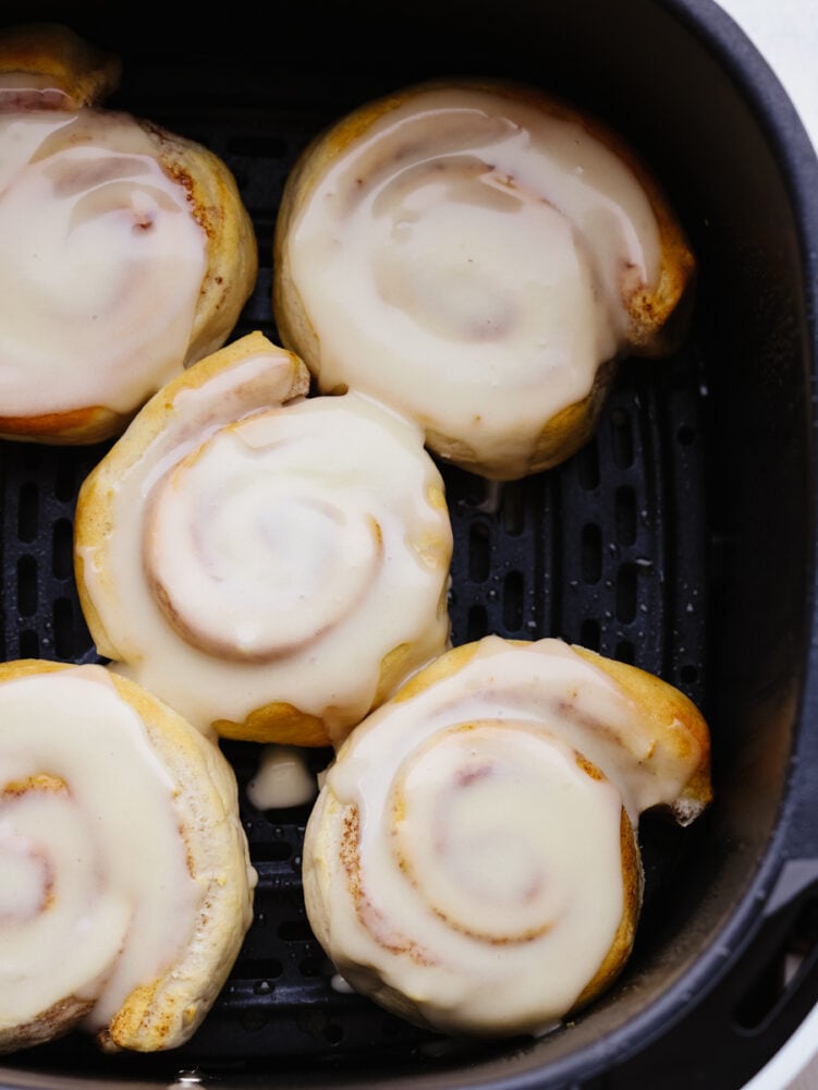 There is no easier way to cook cinnamon rolls out there! These air fryer cinnamon rolls from a can are so easy and delicious. They take less than 15 minutes to cook! Cinnamon rolls in a air fryer basket with frosting.