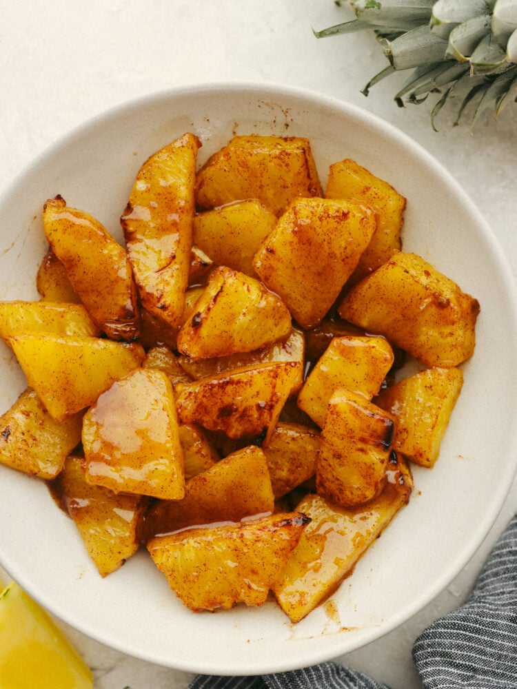 This amazing air fryer brown sugar pineapple is the easiest and most delicious snack! So juicy and sweet, this warm pineapple will become your new favorite way to eat this tropical fruit! A bowl of sliced pineapple pieces with cartelized brown sugar.