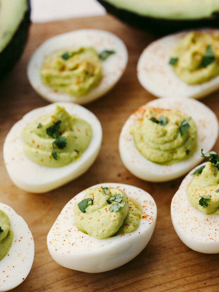 A twist on a classic appetizer, avocado deviled eggs are so creamy and delicious! Flavored with lime and dusted with paprika, your guests won't be able to get enough of this flavorful dish! Closeup of avocado deviled eggs dusted with paprika.