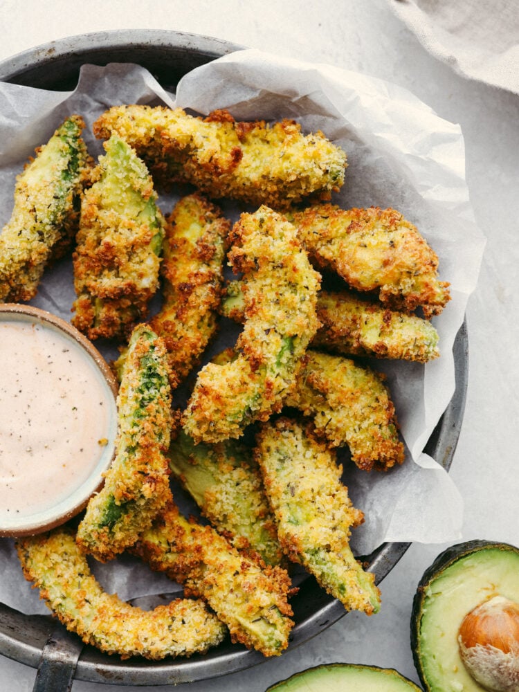 Crispy and creamy, air fryer avocado fries are a quick and easy snack that the whole family will love! They're so delicious and perfect for dipping! Air fryer avocado fries in a basket served with ranch.