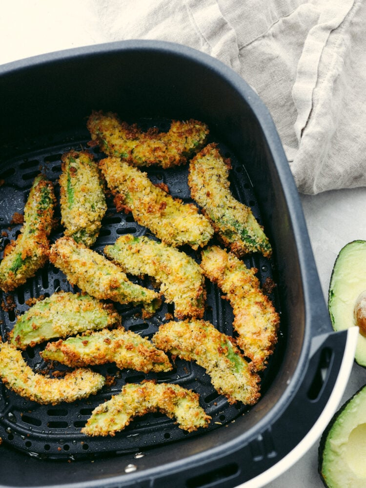Crispy and creamy, air fryer avocado fries are a quick and easy snack that the whole family will love! They're so delicious and perfect for dipping! Avocado fries in the basket of an air fryer.