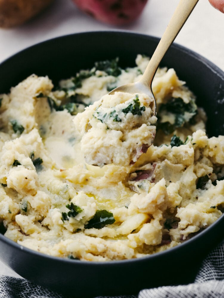 Creamy, buttery, and full of flavor, these Colcannon potatoes will become your new go-to side dish recipe for any meal! They are simple and easy to make and packed with all kinds of delicious ingredients! A close up of a spoon scooping colcannon out of a bowl.