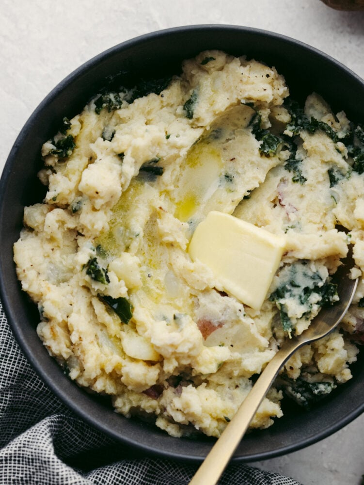 Creamy, buttery, and full of flavor, these Colcannon potatoes will become your new go-to side dish recipe for any meal! They are simple and easy to make and packed with all kinds of delicious ingredients! A bowl filled with colcannon and a spoon, ready to eat.