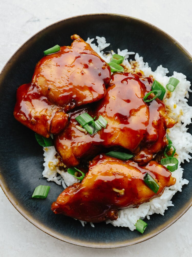 Caramel chicken is an amazing 30-minute meal that you won't be able to get enough of! The chicken is glazed in the best sweet and tangy Asian sauce and is even picky eater-approved! Caramel chicken served over white rice in a black bowl.