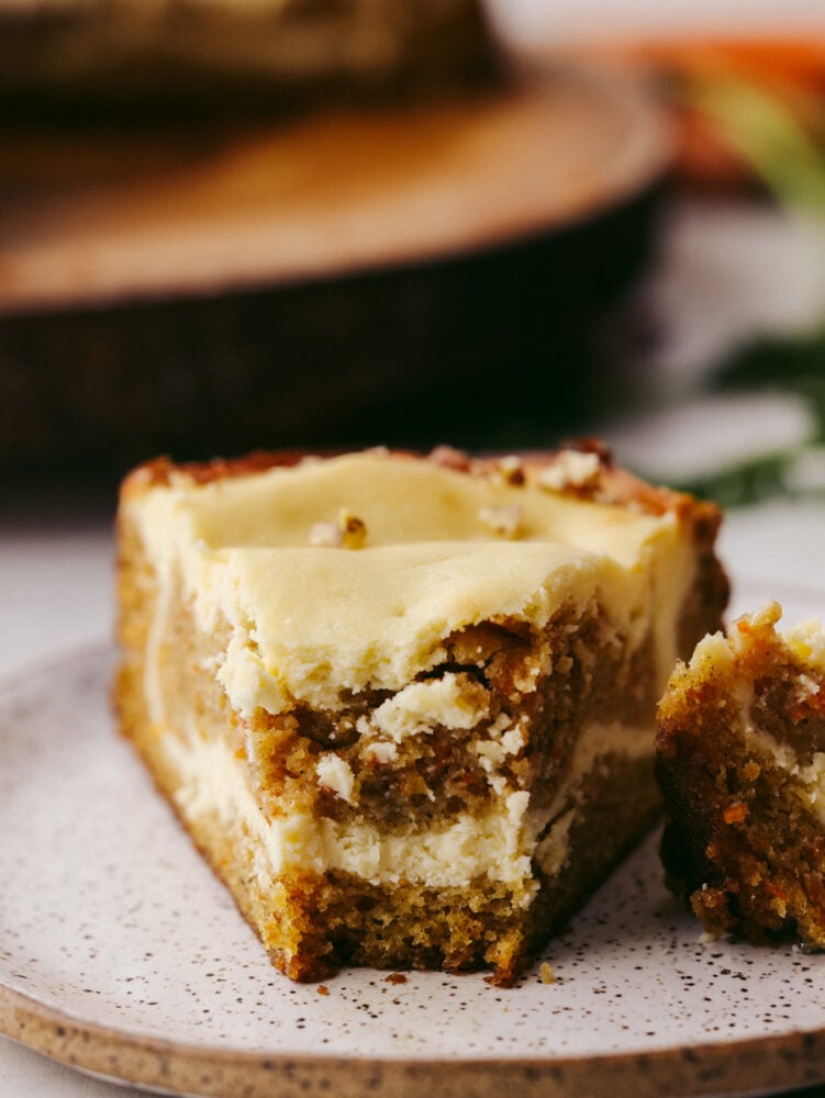 Nutty, sweet, and decadent, each bite of carrot cake cheesecake is a dream! This dessert is so good you wonโt want to stop at one piece! Closeup of a slice of carrot cake cheesecake with a bite taken out of it.