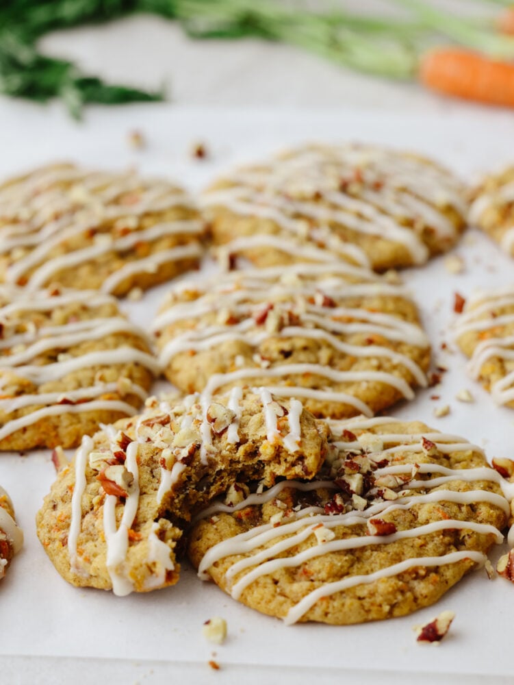 Carrot cake cookies are chewy and sweet with the best hint of warm spice! Drizzled with tangy cream cheese icing, you won't be able to get enough of this sweet treat! Closeup of a carrot cake cookie with a bite taken out of it.