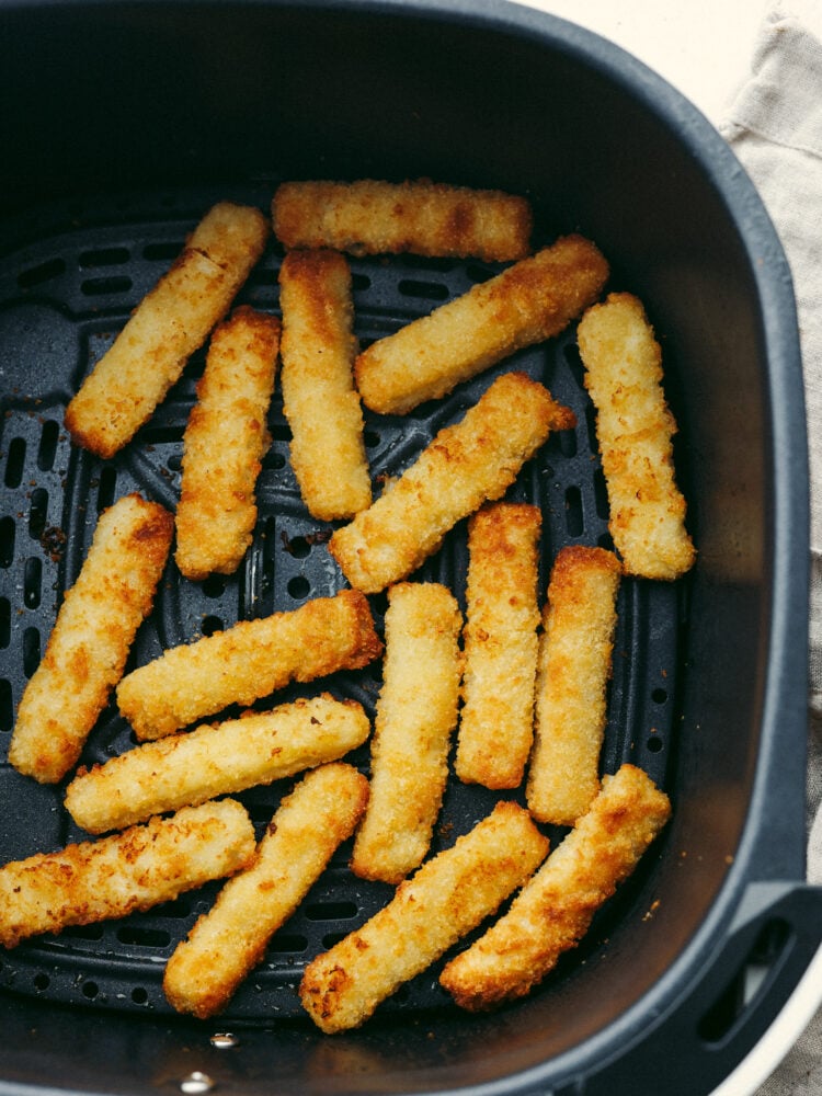 You're going to love how easy it is to make frozen fish sticks in the air fryer! They're golden, delicious, and ready for your favorite dips. Frozen fish sticks in the basket of an air fryer.