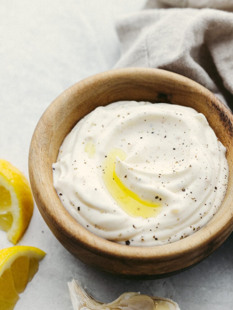 This garlic aioli sauce is dreamy! The hint of lemon flavor combined with garlic has my mouth watering. It's packed with enough flavor to make anything that you dip into it that much more delicious. Garlic aioli sauce in a little wooden serving bowl.