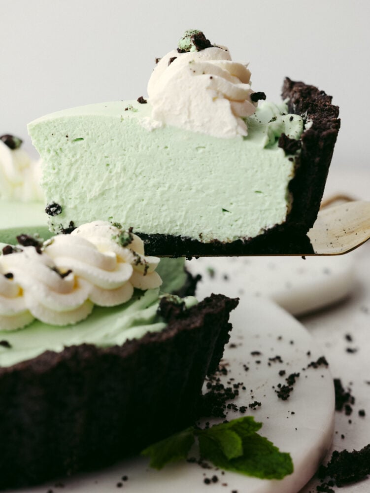 This chilled, minty pie grasshopper pie has a creamy filling sitting on an Oreo cookie crust. The taste and smooth texture are perfect and will have just about anyone coming back for seconds! The side view of a slice of pie being taken out with a pie server.