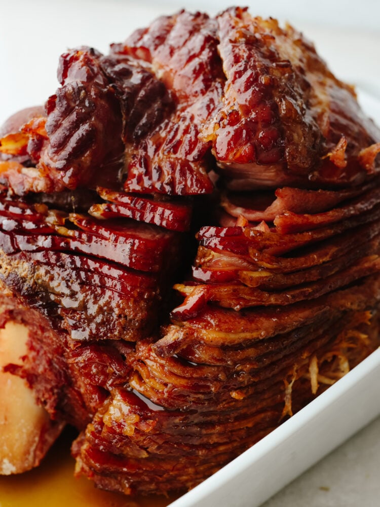 This instant pot ham is juicy, full of flavor, and cooked so that there is a caramelized glaze, making this ham taste like a slice of heaven! It will have every guest at your dinner table asking for the recipe! A close up of a ham after cooking it in an instant pot, sliced with a glaze and ready to eat.