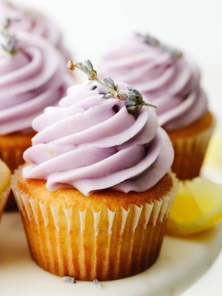 These lovely lavender cupcakes are delicate and delicious. The cake base is lavender flavored and has a lemon buttercream frosting on top, making them perfect for any special occasion! A close up of a lavender cupcake.