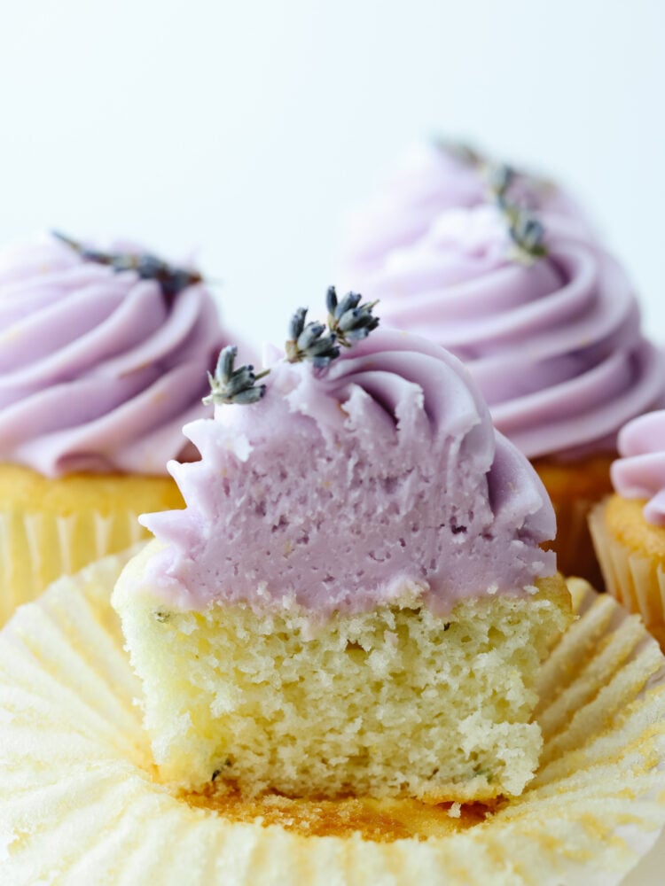These lovely lavender cupcakes are delicate and delicious. The cake base is lavender flavored and has a lemon buttercream frosting on top, making them perfect for any special occasion! A lavender cupcake cut in half.