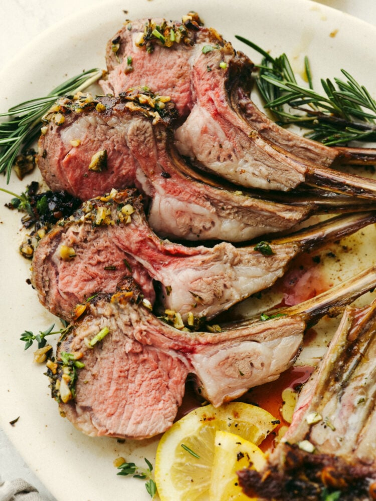 Mouthwatering and delicious, this garlic herb-crusted rack of lamb is the most amazing main dish that you could ever offer to your guests! Beautiful, delicious, and impressive; it checks all of the boxes! A plate with 4 pieces of the rack of lamb.