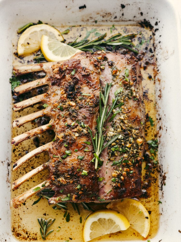 Mouthwatering and delicious, this garlic herb-crusted rack of lamb is the most amazing main dish that you could ever offer to your guests! Beautiful, delicious, and impressive; it checks all of the boxes! The top view of the rack of lamb in the baking dish, cooked and resting.