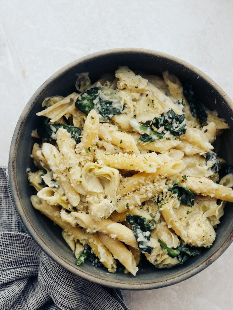 Spinach artichoke pasta is the perfect marriage of hearty and fresh! These ingredients complement each other and blend together so seamlessly that you will be asking for seconds in no time! A bowl of spinach artichoke pasta.