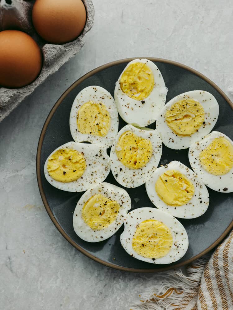 These perfectly cooked air fryer hard-boiled eggs will blow your mind! Convenient, quick, and easy to peel every time, they will be your go-to for some quick protein for any meal! A plate of sliced, hard boiled eggs sprinkled with salt and pepper.