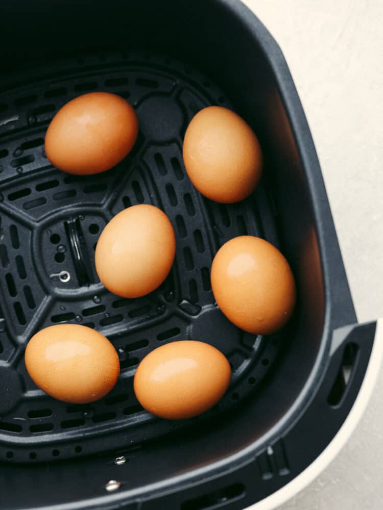 These perfectly cooked air fryer hard-boiled eggs will blow your mind! Convenient, quick, and easy to peel every time, they will be your go-to for some quick protein for any meal! A close up of 5 brown eggs in the air fryer.