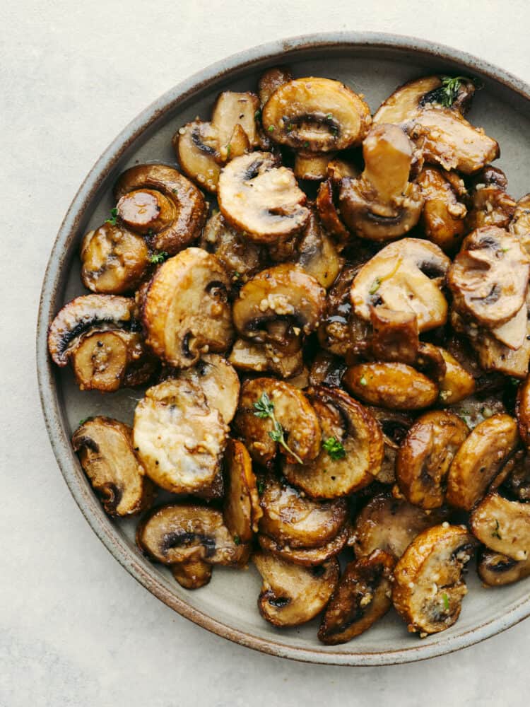 Confession: I never thought I liked mushroomsโฆ until I made these air fryer mushrooms. With garlic parmesan, theyโre juicy, tender, and downright addictive. Even the mushroom skeptics at your table will be fighting over the last bite! Top-down view of garlic parmesan air fryer mushrooms on a gray plate.