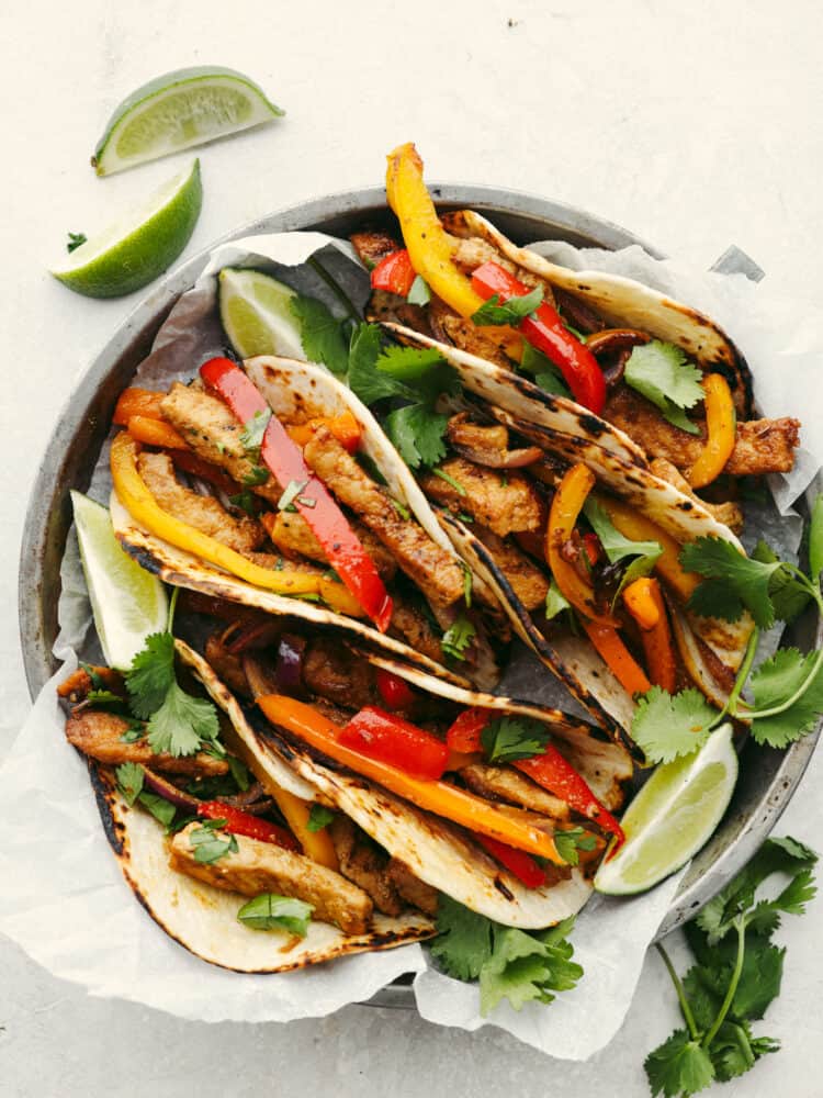 Celebrate with these insanely delicious and easy air fryer pork fajitas! They are restaurant-quality fajitas in the comfort of your own home, and your entire family will go crazy over them! A pork fajita on a silver pie tin with parchment paper.