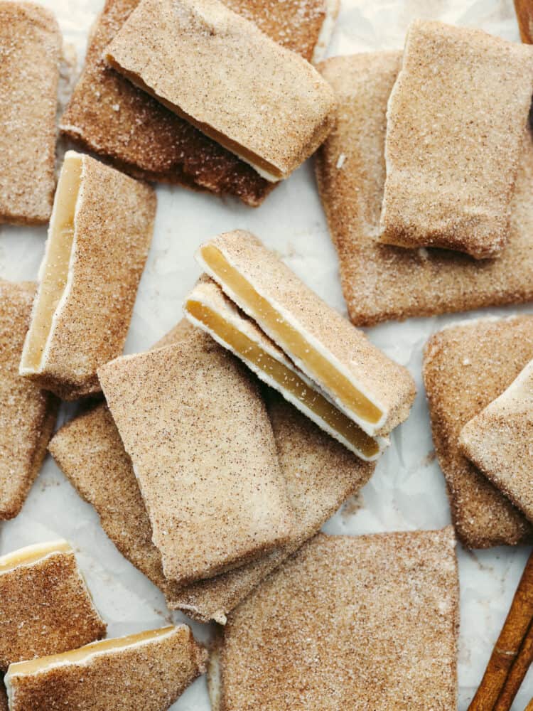 This churro toffee is covered in delicious white chocolate, sprinkled with cinnamon sugar, and leaves your mouth watering after just one bite! It's better than the stuff found at Disneyland, AND you can make it at home! The top view of churro toffee in broken pieces on parchment paper.