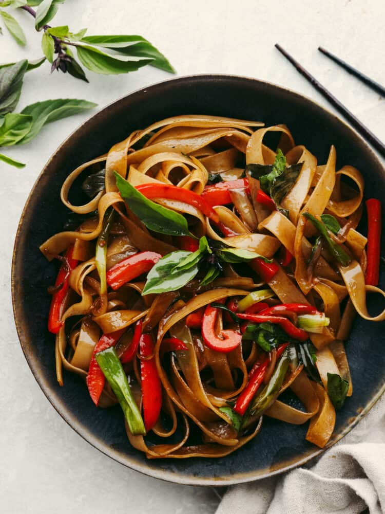 These drunken noodles (or spicy Thai noodles) are filled with delicious flavors! Coated in a perfectly savory sauce, these noodles will satisfy any Thai food craving! A bowl of drunken noodles ready to eat with chopsticks on the side.