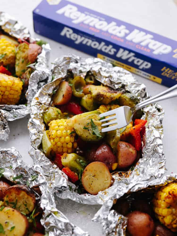 These foil pack grilled vegetables made with Reynolds Wrap® Heavy Foil are perfect for BBQ season! They cook just right on your grill and come out tender and seasoned to perfection. This is one side dish that you don't want to miss! Vegetables in the foil pack with a fork.