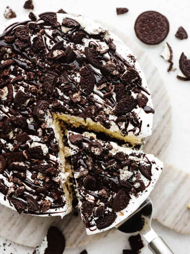 Ice cream cake is the best of both worlds...ice cream in the form of a cake! This cookies and cream ice cream cake is exploding with layers of oreo cookies, ice cream, and gooey fudge sauce. The top view of an ice cream cake with a. slice being pulled out with a cake server.