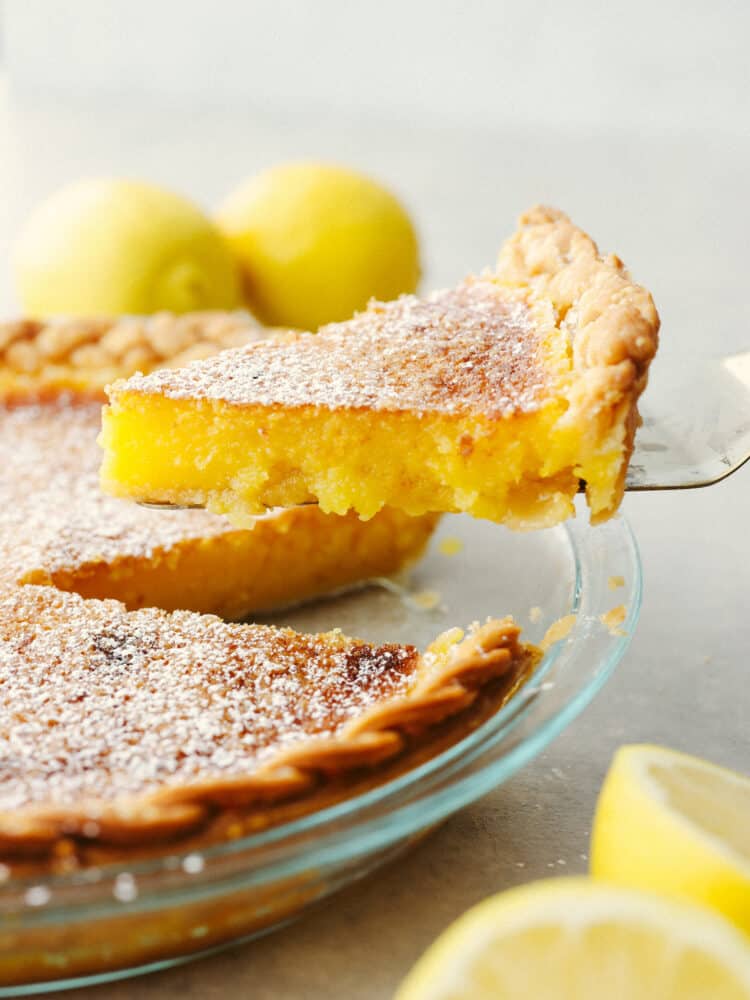 This lemon chess pie is packed purely with lemon filling and is a lemon-lovers dream come true! The texture is smooth and creamy with a deliciously flakey crust that just about anyone will go crazy for! A lemon chess pie with a slice being taken out with a pie server.