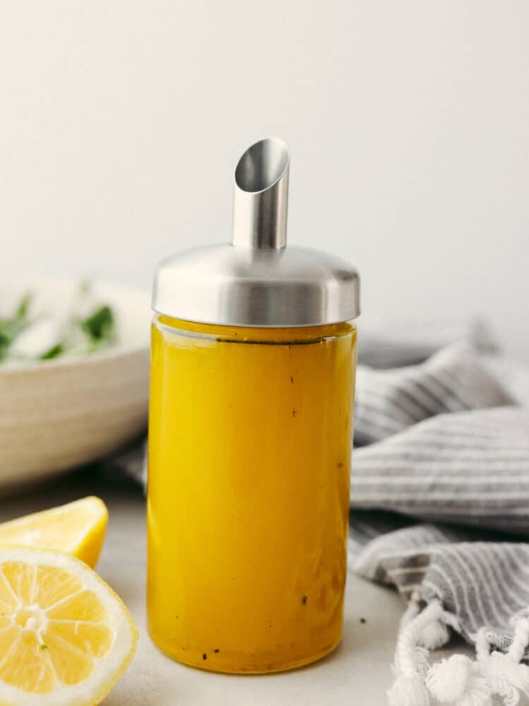 This lemon vinaigrette salad dressing is bright, zesty, and packed with flavor. It will elevate any salad that you put it on, and you will never go back to any other dressing! A bottle filled with lemon vinaigrette dressing with a silver pour spout.