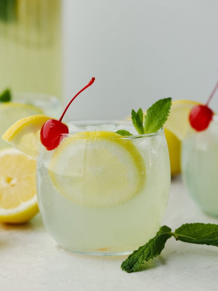 If you are looking for a delightfully refreshing, non-alcoholic drink to get you through all of the hot summer days ahead, this Mint Julep is it! The cool flavorings of mint, cherry, and lemon mix together to create an array of flavors that will satisfy your thirst! The side view of mint julet in a clear class cup garnished with a cherry, lemon and mint sprig.