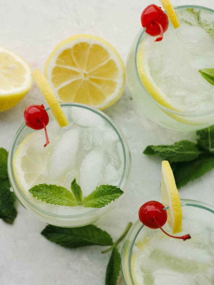 If you are looking for a delightfully refreshing, non-alcoholic drink to get you through all of the hot summer days ahead, this Mint Julep is it! The cool flavorings of mint, cherry, and lemon mix together to create an array of flavors that will satisfy your thirst! The top view of glass cups filled with mint julep and garnished with cherries, lemons and mint sprigs.