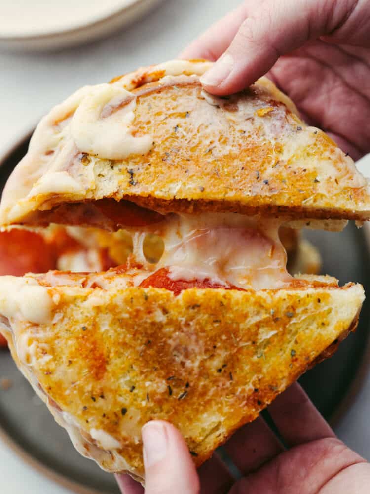 This amazing pizza grilled cheese has all the melty goodness of a classic grilled cheese sandwich combined with the flavor of pepperoni pizza! It's a quick and easy meal everyone in your family will love. Closeup shot of a sliced sandwich being pulled apart in 2 halves.