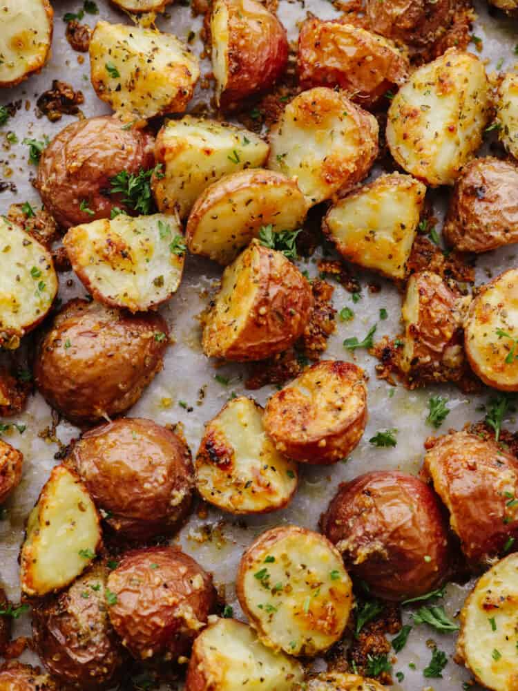 Parmesan garlic roasted potatoes have a crispy edge and tender center. Their mouthwatering parmesan garlic flavor makes them the perfect side! Closeup of potatoes, covered with parmesan and herbs.