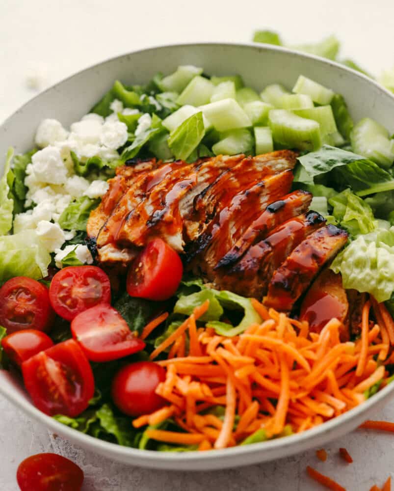 This buffalo chicken salad is packed with fresh vegetables, feta cheese, and the perfect buffalo chicken. Layer this with some homemade dressing, and you'll have your new go-to salad recipe! Buffalo chicken salad in a bowl without dressing.