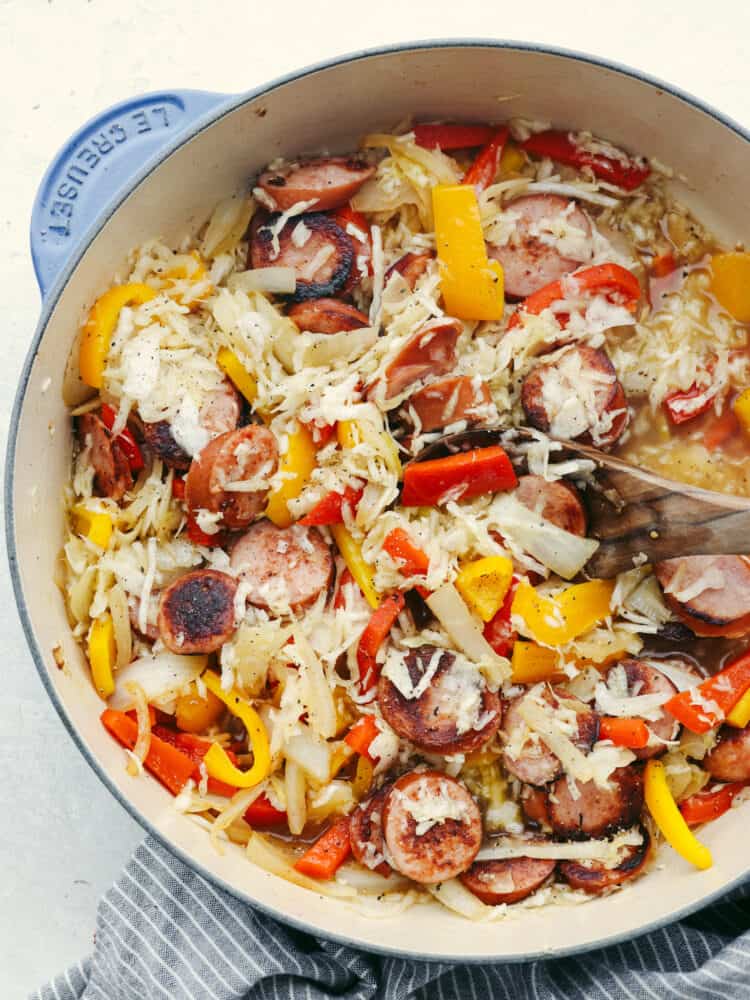 and flavored kielbasa layered in a bed of savory sauerkraut, this is a meal that your entire family will love! It's packed full of veggies and it's ready to eat in less than 30 minutes! Kielbasa and sauerkraut cooket in a skillet on the stove.