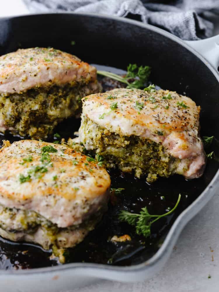 These cheesy stuffed pork chops are juicy and tender and baked to perfection! These not only make any dinner look fancy but they also taste amazing! 3 stuffed pork chops getting browned in a skillet.