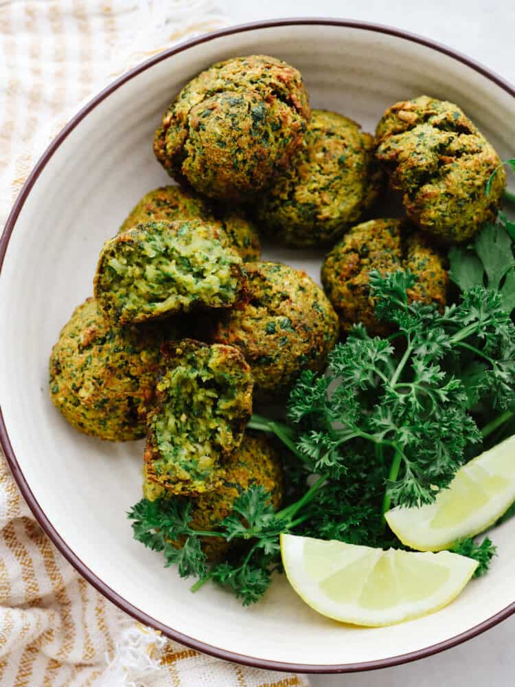 Delicious air fryer falafel is a healthier and easier version without having to fry anything in oil. With a crispy outside shell and a tender center, this falafel is packed with flavor and nutrition. Overhead photo of crispy falafel balls in a bowl and garnished with fresh herbs.