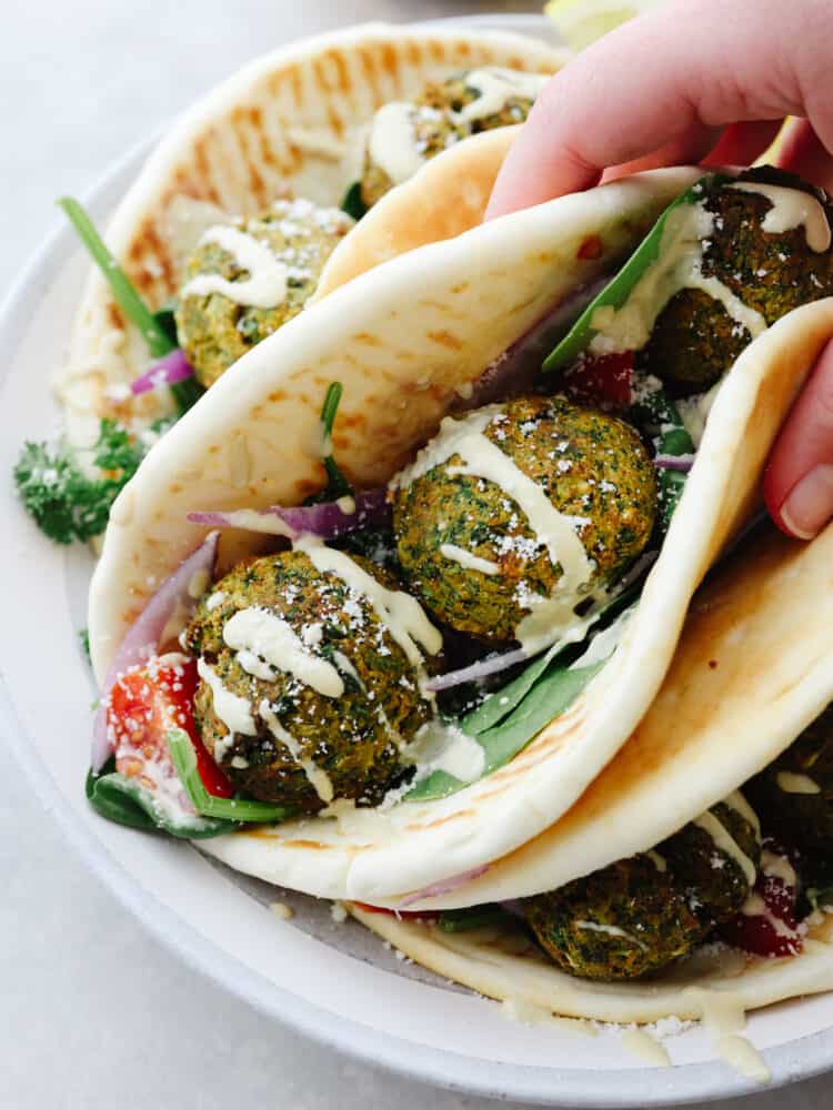 Delicious air fryer falafel is a healthier and easier version without having to fry anything in oil. With a crispy outside shell and a tender center, this falafel is packed with flavor and nutrition. Photo of a handheld wrap. Falafel balls served inside a wrap with lettuce, tomato, and a drizzle of tzaziki sauce.