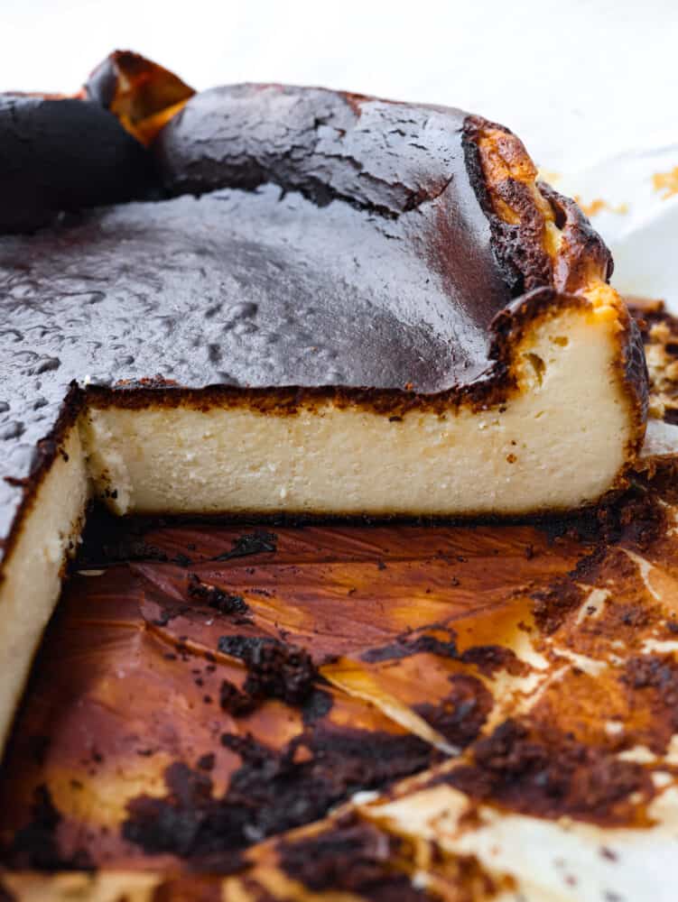 Try not to judge Basque cheesecake by its burnt outer layer because it's meant to be caramelized to perfection. You will be blown away by the rich and creamy Inside of this unique cheesecake. A side view photo of the cheesecake with a large slice cut out of it. The view is of the inside of the creamy cheesecake.