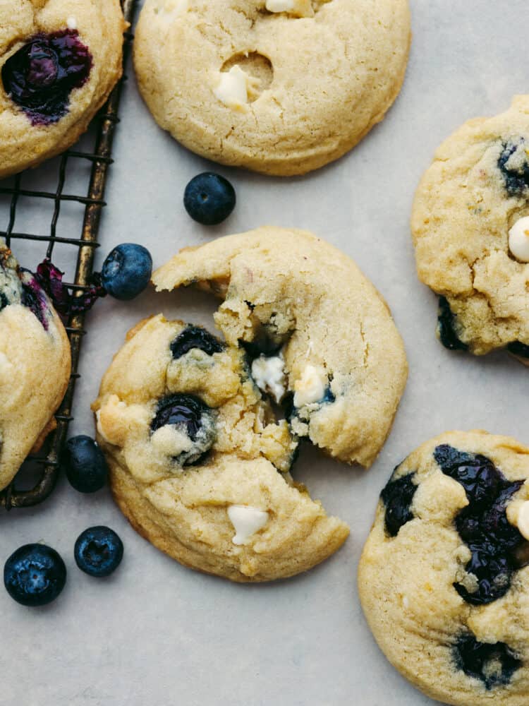 These blueberry cookies are packed with plump blueberries, white chocolate, and zesty lemon for an irresistible flavor combination! Bright, juicy, and sweet, this is one summer cookie recipe you wonโt want to miss. Closeup of a blueberry white chocolate cookie, broken in half.