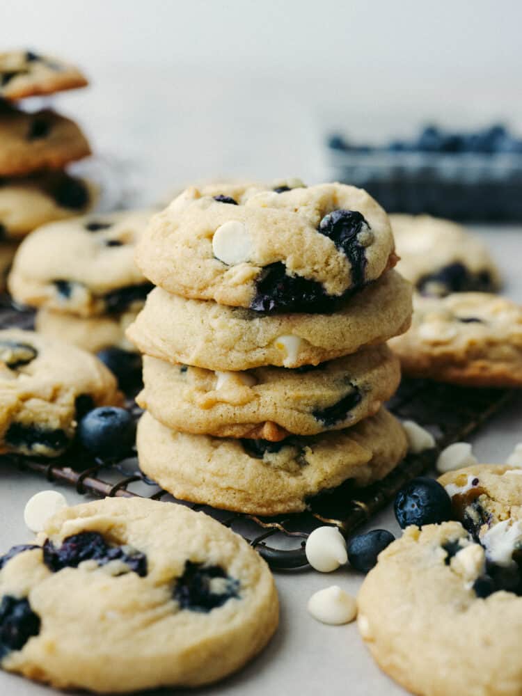 These blueberry cookies are packed with plump blueberries, white chocolate, and zesty lemon for an irresistible flavor combination! Bright, juicy, and sweet, this is one summer cookie recipe you wonโt want to miss. 4 blueberry cookies stacked on top of each other.