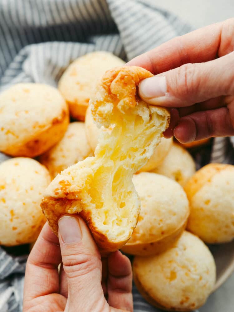 This delicious Brazilian cheese bread has a perfect combination of delicious taste and texture. Filled with pockets of airy goodness that taste so cheesy, you won't be able to stop at just one! A close up of a Brailian cheese bread being broken in half.