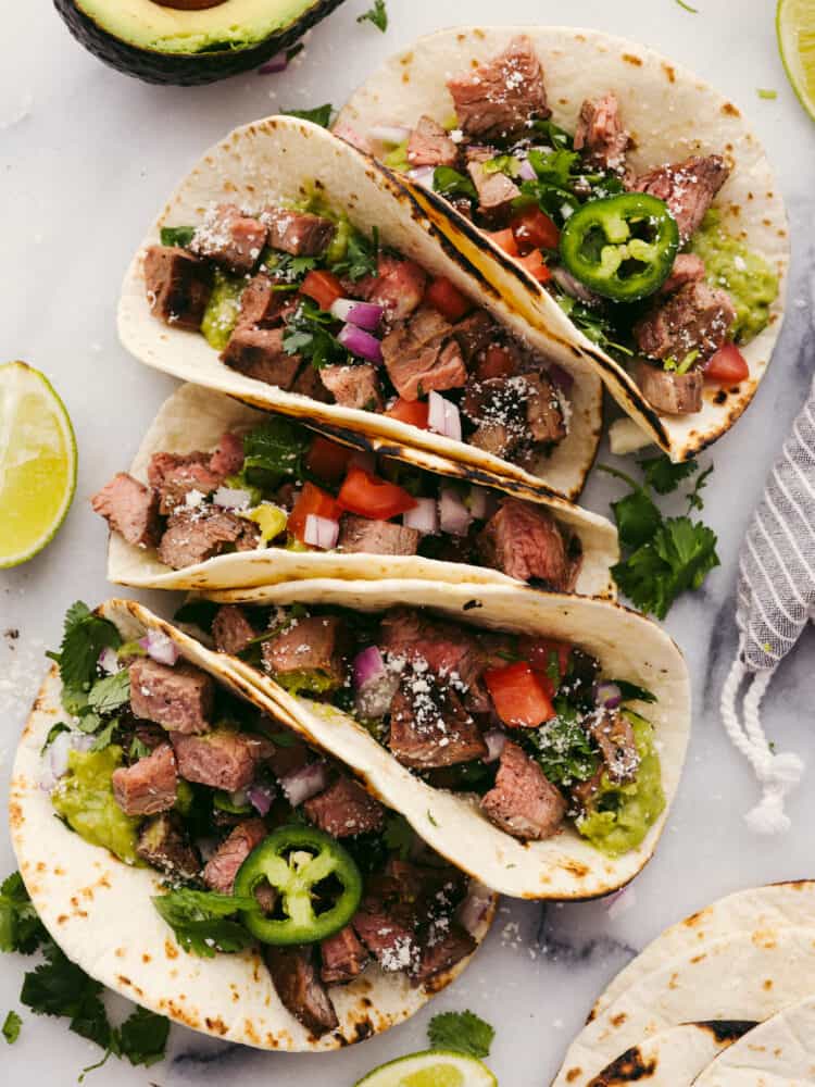 Carne asada tacos are a go-to recipe in our family! You can fill the tortilla to the brim with all of your favorite toppings, and everyone (even picky eaters!) will go crazy over this meal! The top view of assembled carne asada tacos.