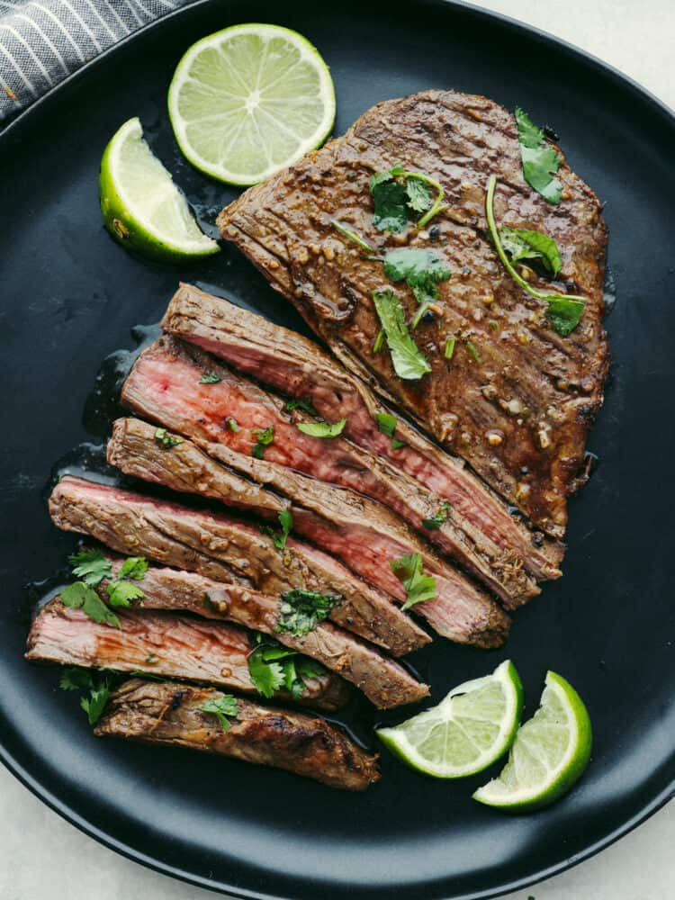 No more firing up the grill to enjoy juicy and tender steak. This flavorful flank steak comes together quickly after it is marinated and air-fried to perfection! Top-down view of sliced flank steak on a black plate, ready to serve.