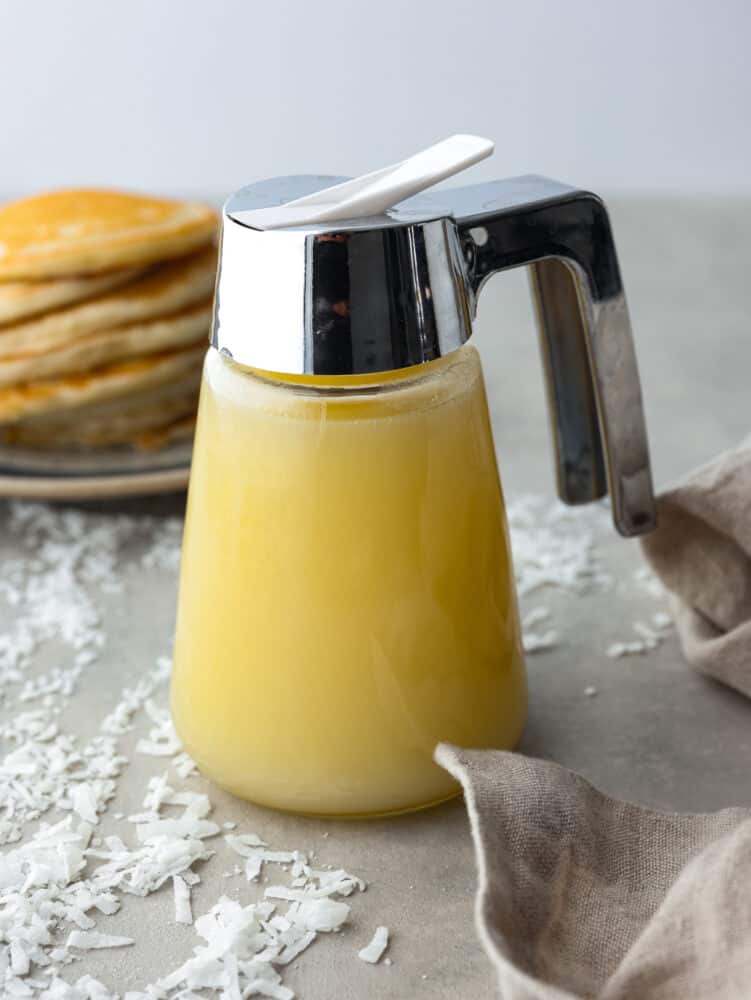 Coconut syrup is going to be your new favorite breakfast addition! Itโs creamy, sweet, and will coat pancakes and waffles in delicious, nutty flavor. Coconut syrup in a syrup pitcher.