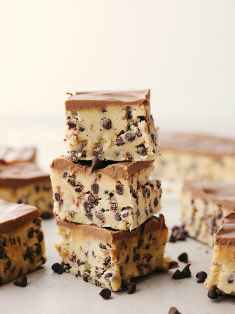 Get ready for these chocolate chip cookie dough bars to become a favorite you makeย all the time!ย Perfectly creamy and delicious (and with no raw egg), these bars will get devoured by anyone lucky enough to eat them! A stack of chocolate chip cookie dough bars.