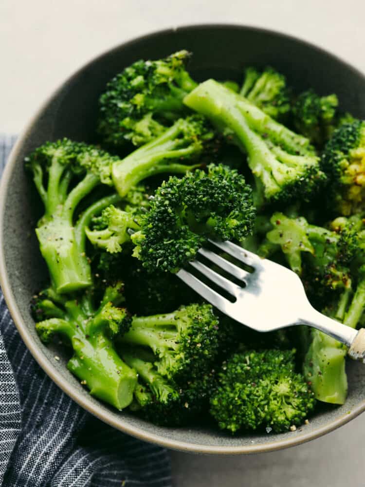 Air fryer frozen broccoli is so easy and delicious! Whip up that classic roasted broccoli texture and flavor with no mess (and in under 10 minutes!) so that it can go with any meal! Broccoli in a bowl with a silver fork, ready to eat.