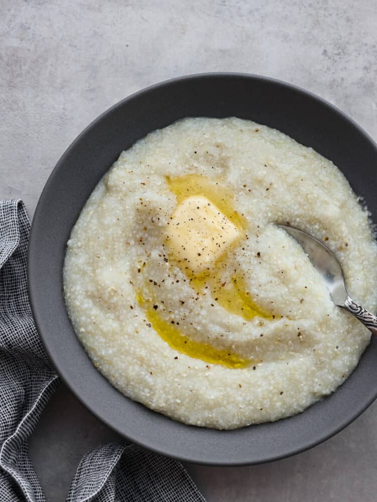 Southern grits are the perfect breakfast (or lunch or dinner!) option. They are the creamiest and most delicious addition to your morning meal, and everyone in your family will be able to make these. They are that easy! The top view of a bowl of grits with butter and pepper on top.